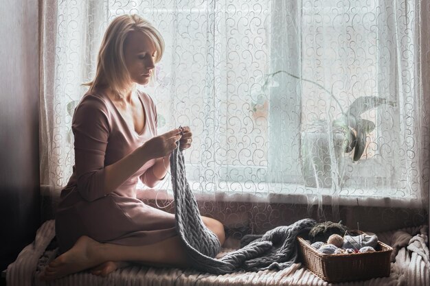 Osoba haftująca przy oknie